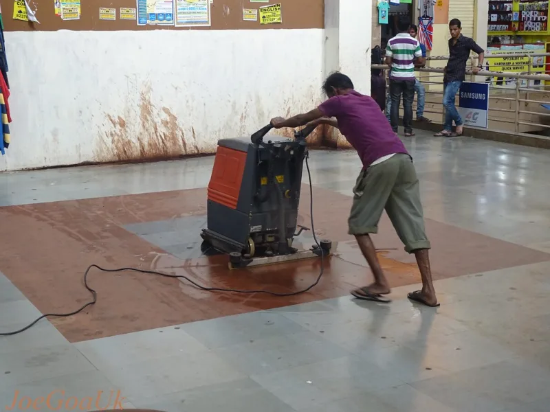 Un homme passe une machine de lavage sur un sol carrelé mouillé
