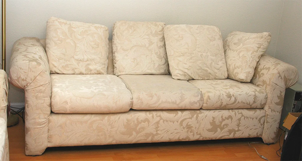 Un canapé trois places en tissu écru et ses coussins