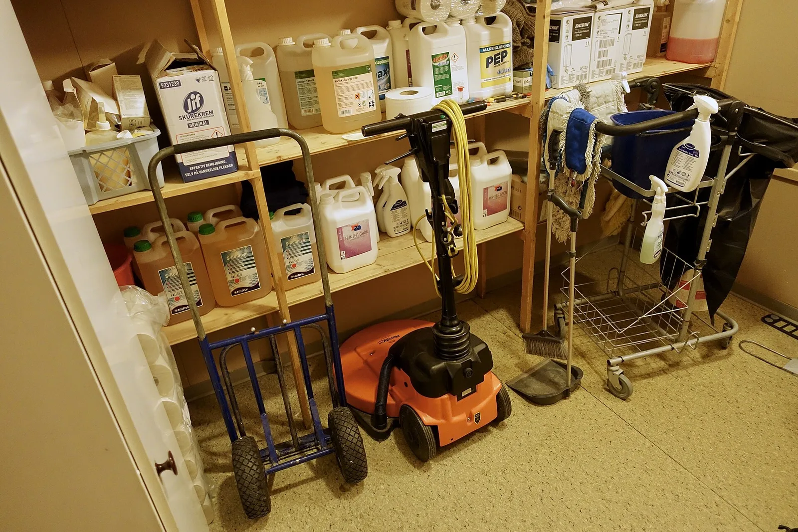 Un local d’entretien : bidons de produits, monobrosse et chariots de ménage