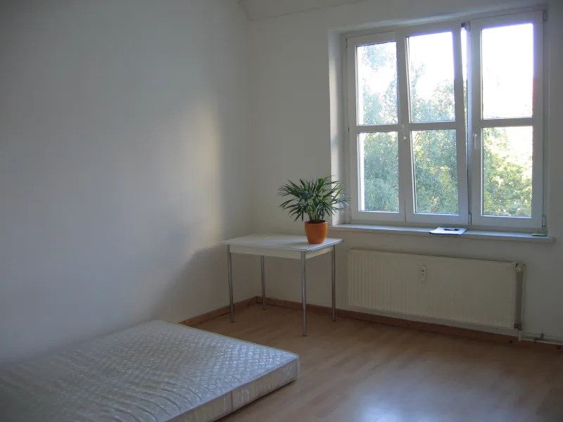 Un matelas nu posé au sol d’une chambre vide, près d’une fenêtre
