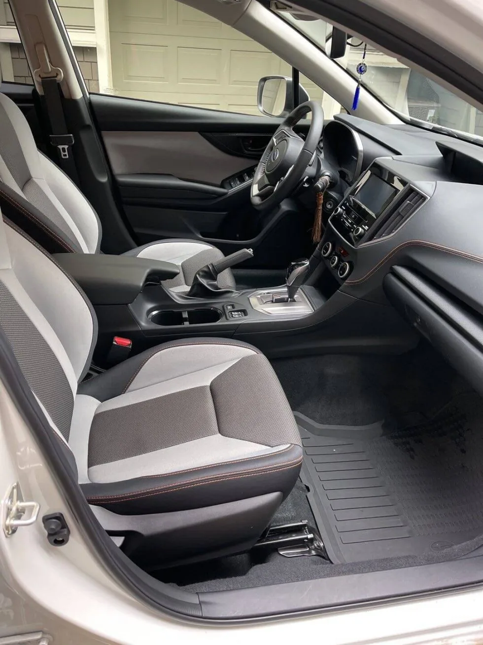 Les sièges avant en tissu gris d’une voiture, vus par la portière