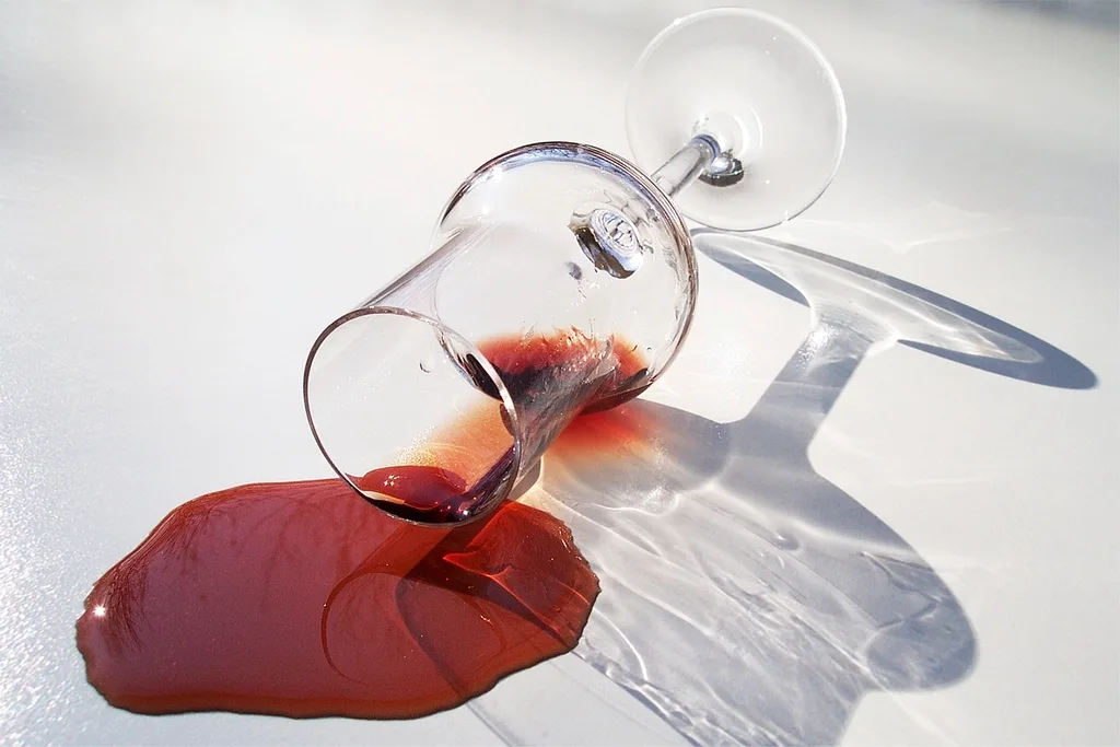 Un verre de vin rouge renversé, le vin répandu en flaque