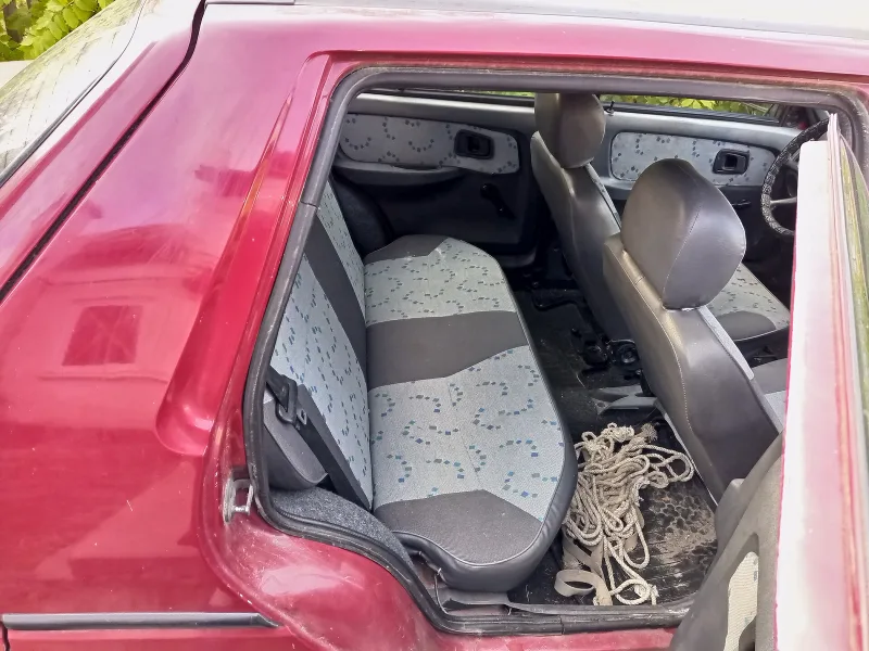 La banquette arrière en tissu d’une petite voiture rouge, portière ouverte