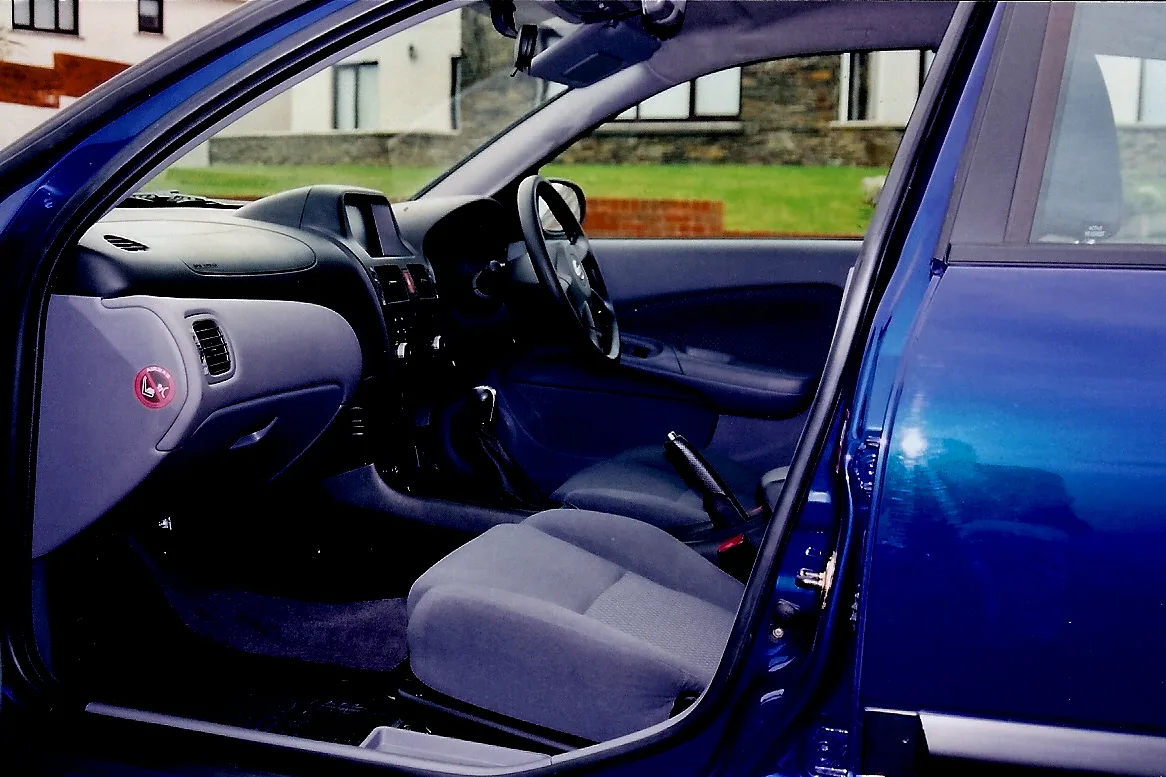 Une voiture bleue portière ouverte, ses sièges en tissu